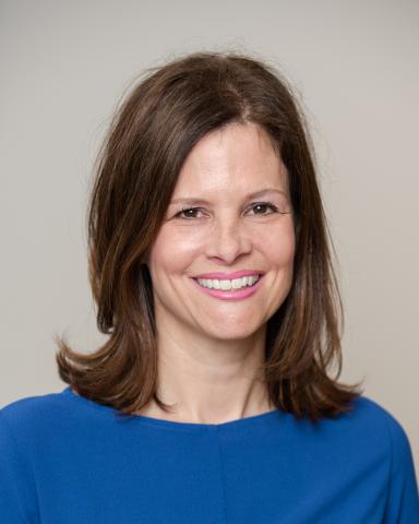 White woman inn blue shirt smiels in front of white background