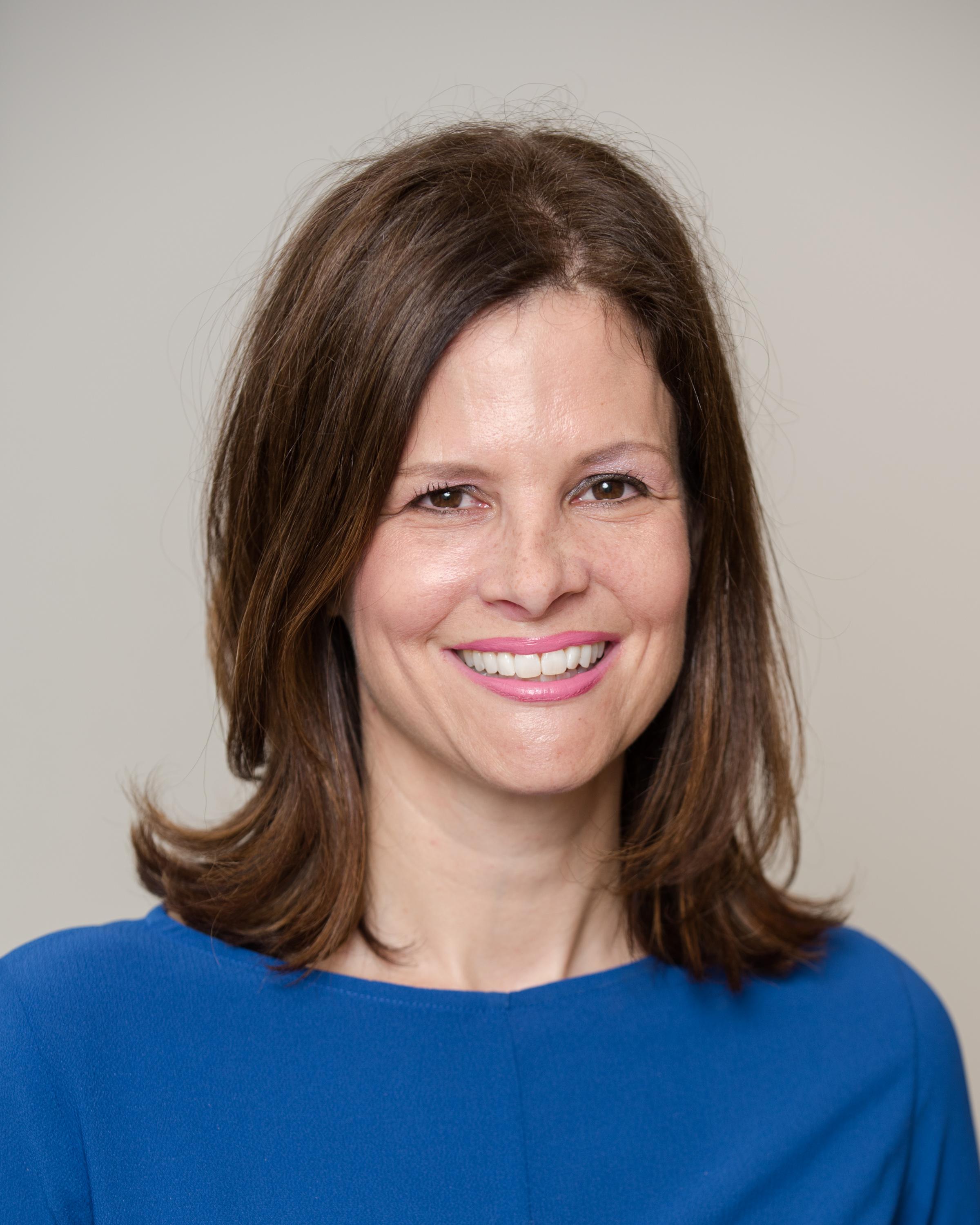 White woman inn blue shirt smiels in front of white background
